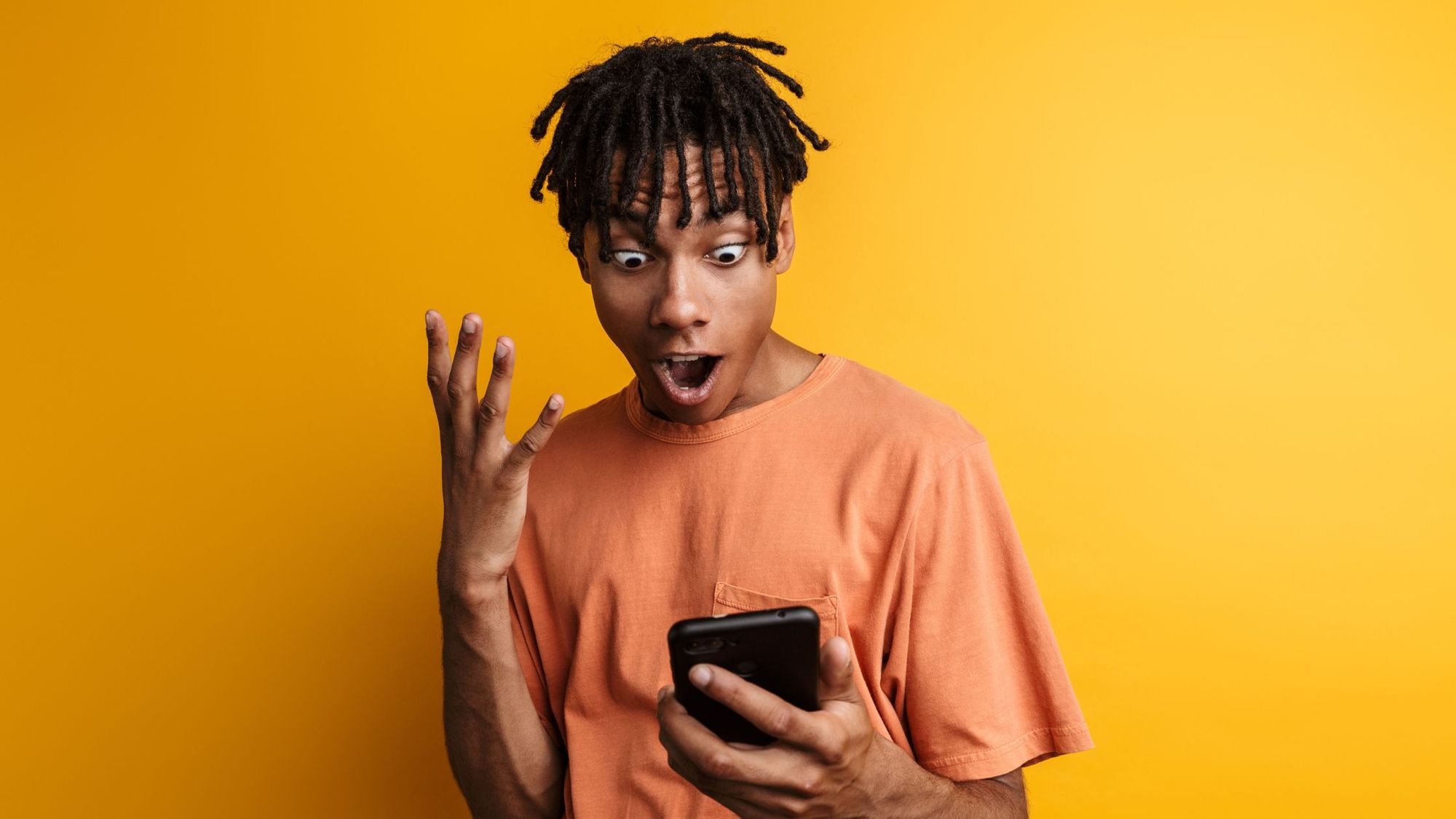 Young man celebrating ordering his first pair of nike sneakers on his phone.